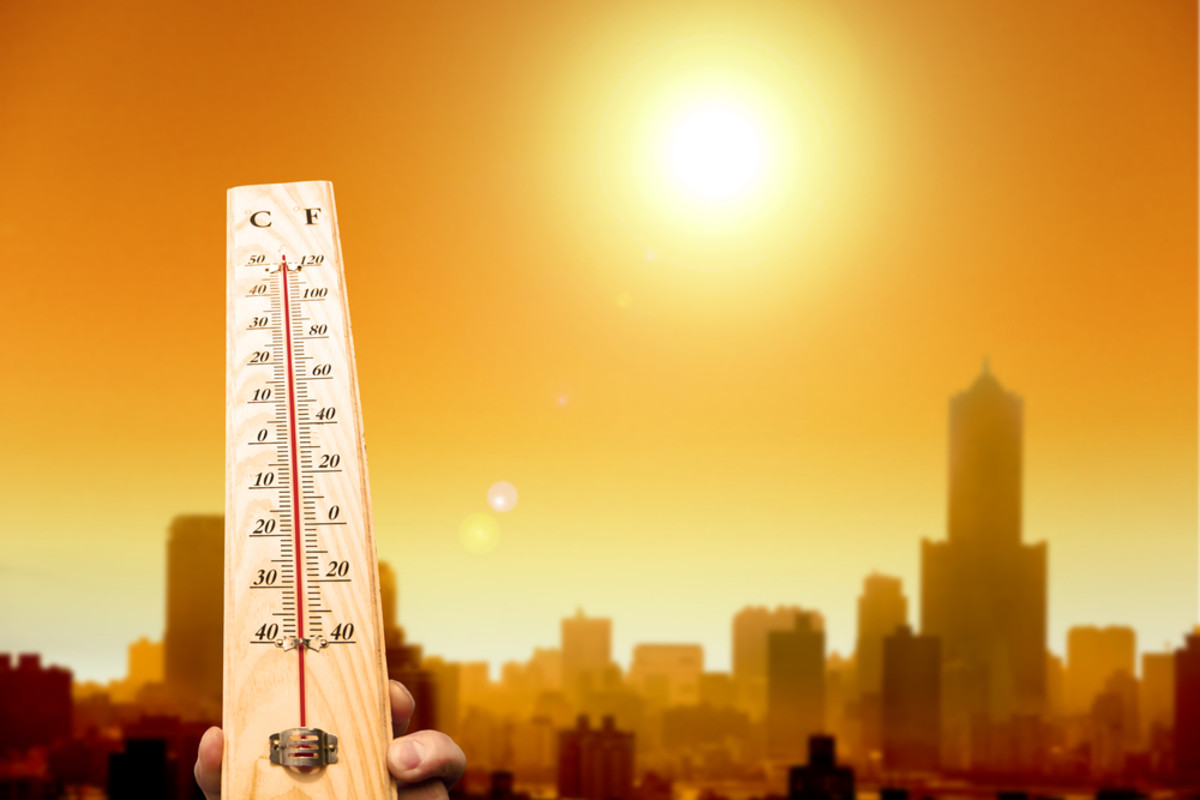 A thermometer with a high temperature in front of a sunny orange cityscape.