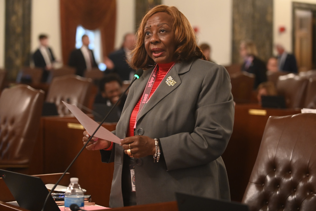 Senator Hunter holds a piece of paper and speaks into a microphone while at her desk in the Senate chamber.