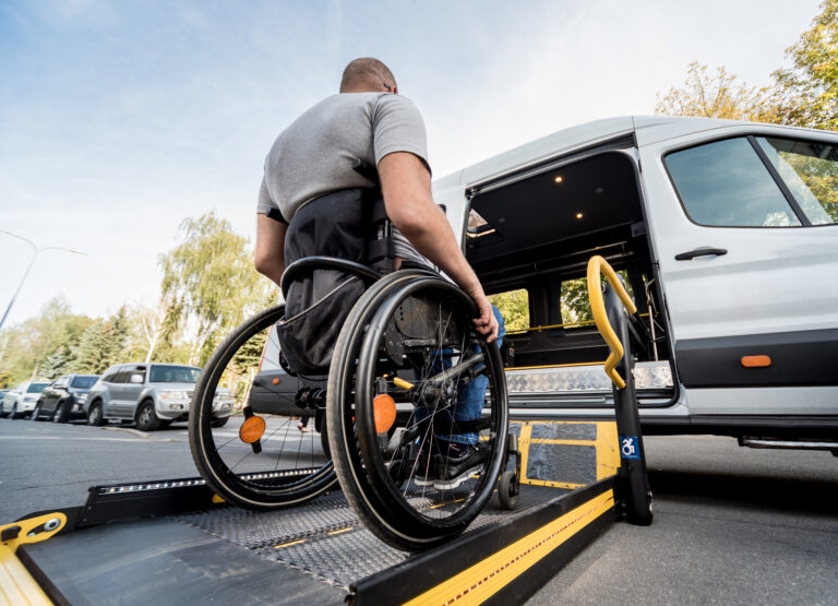 A man moves his wheelchair onto a ramp of a van.