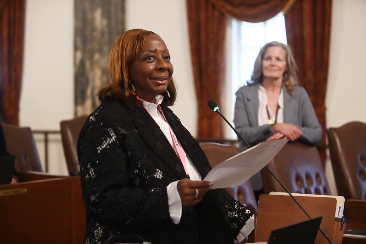 Senator Hunter standing and holding a piece of paper while smiling.